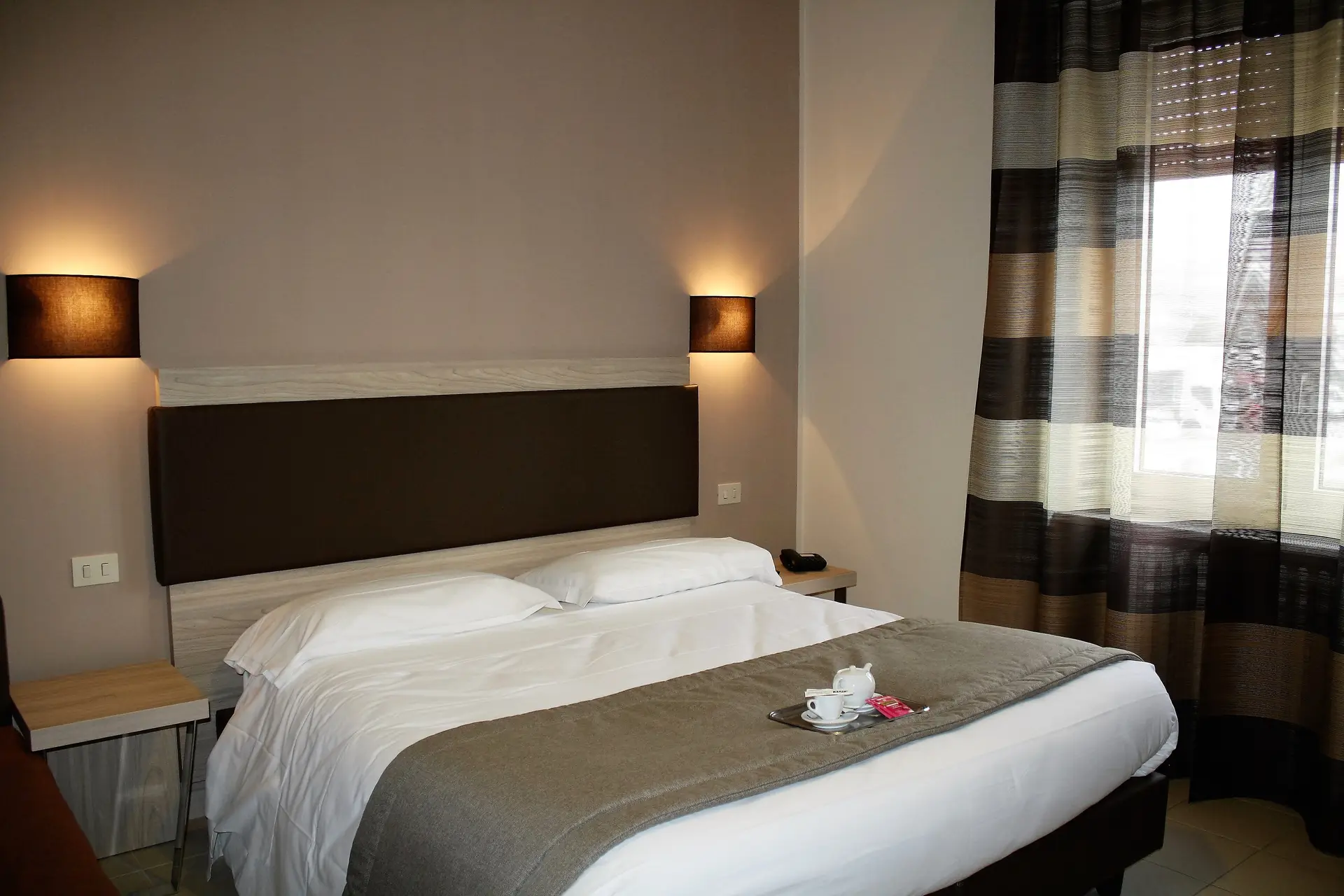 Modern bedroom with double bed and curtain.