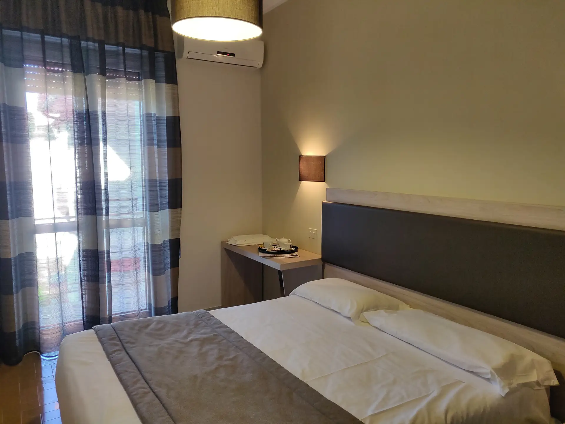 Camera da letto con letto matrimoniale e finestra con tende.