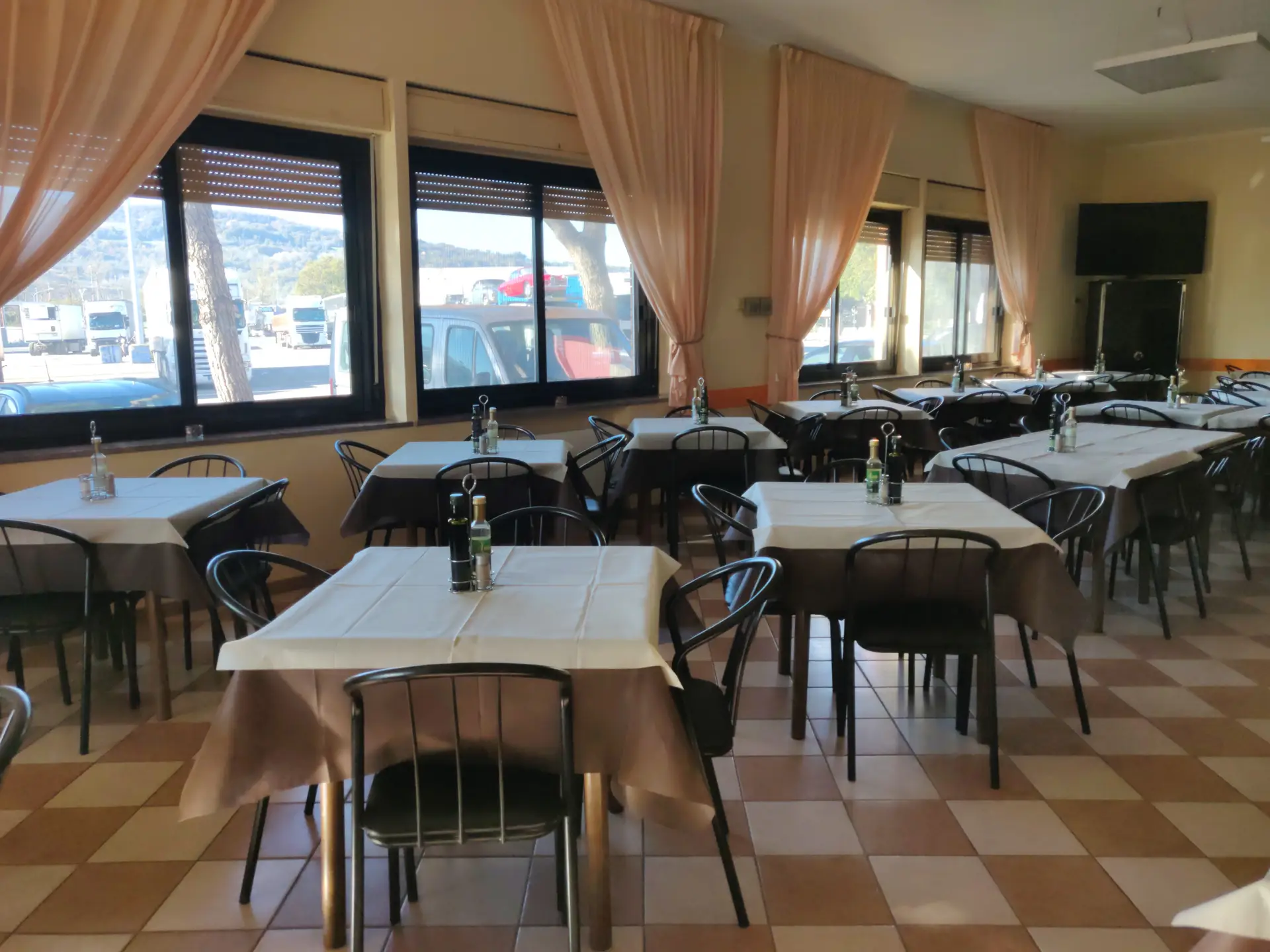 Sala ristorante con tavoli apparecchiati e finestre ampie.
