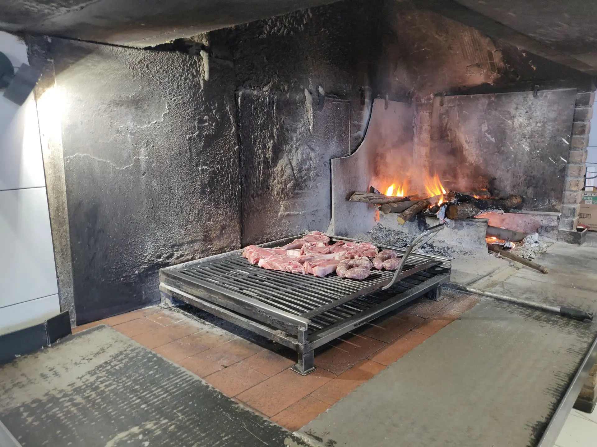 Carne alla griglia su barbecue con fuoco acceso.
