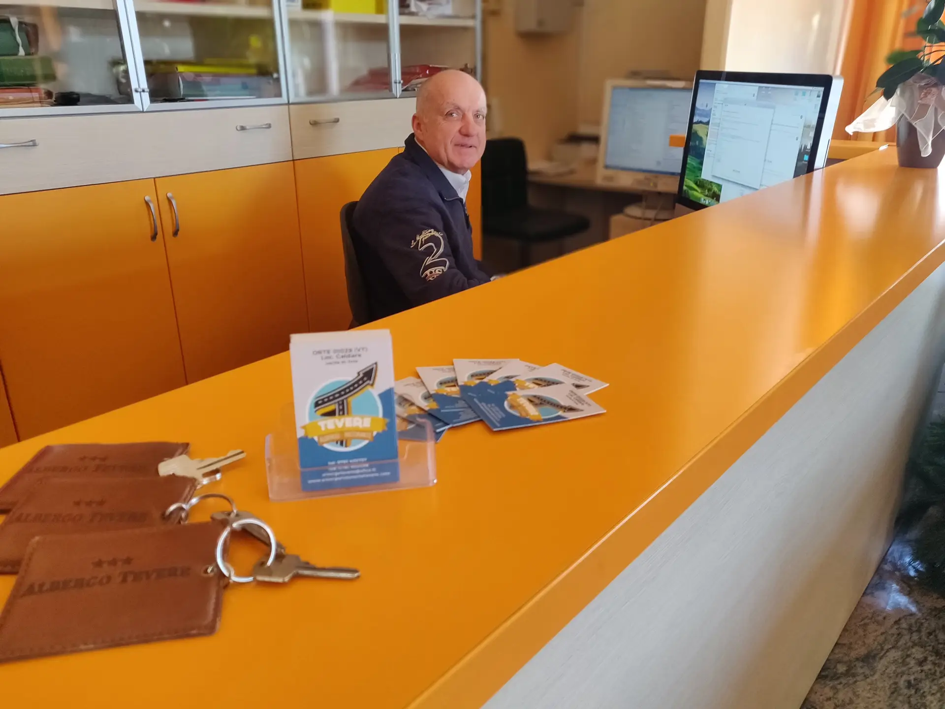 Receptionist seduto dietro il bancone di un hotel.