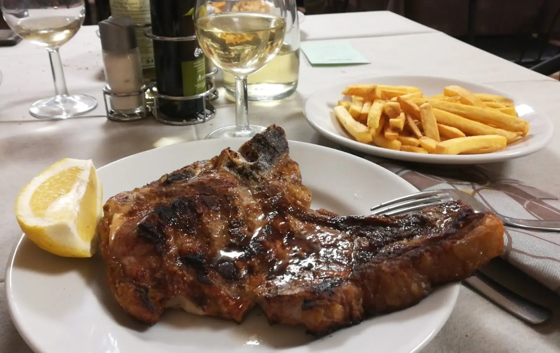 Bistecca con patatine fritte e bicchiere di vino.