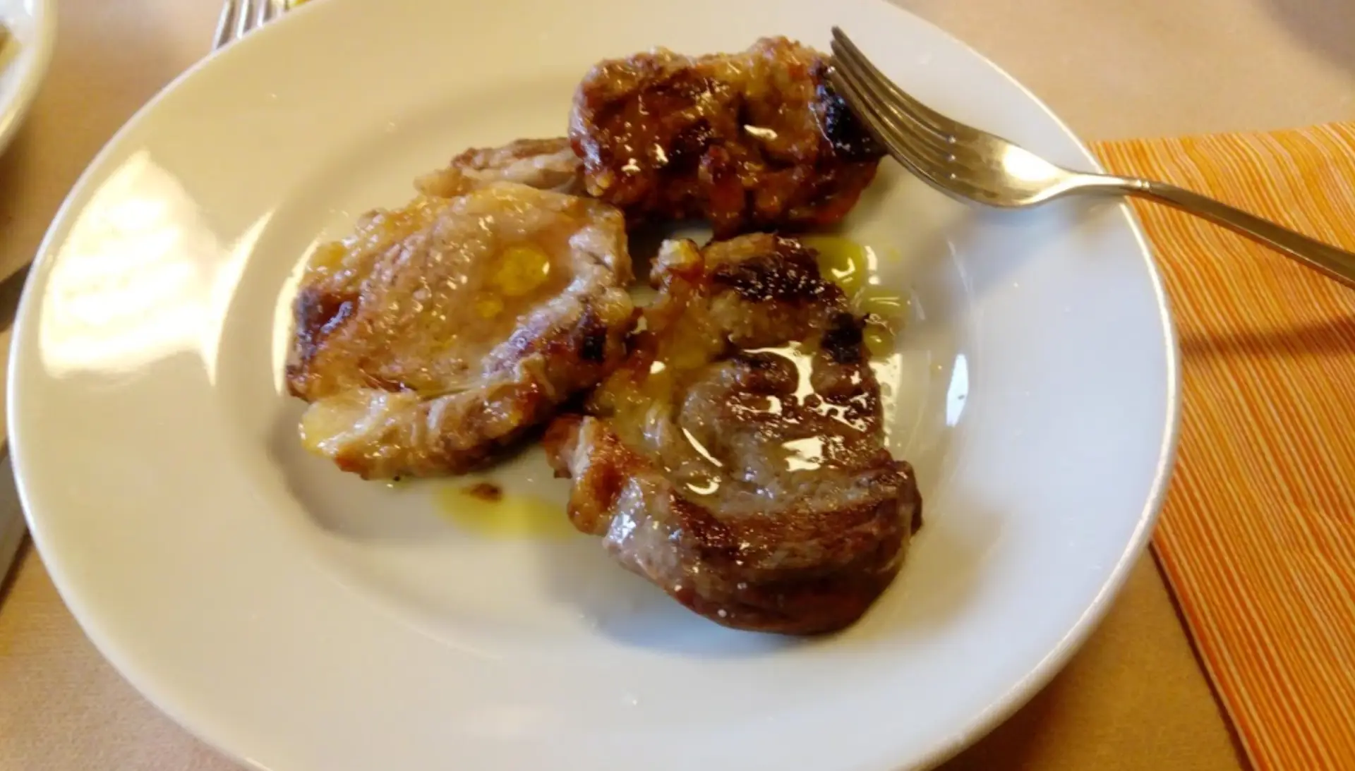 Tre fette di carne su piatto bianco.