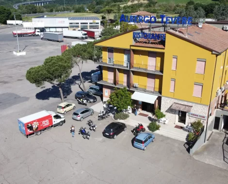 Parcheggio con camion e albergo giallo sullo sfondo.