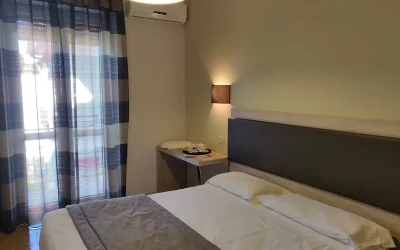 Camera da letto con letto matrimoniale e finestra con tende.