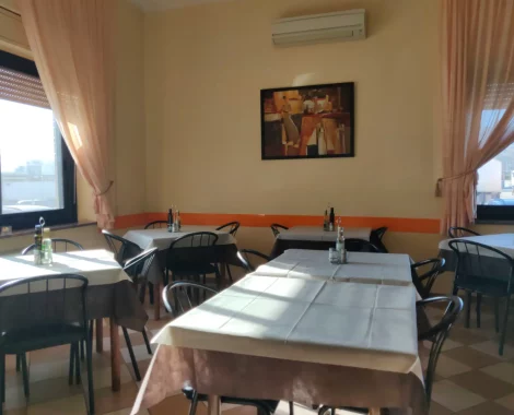 Sala da pranzo con tavoli apparecchiati e quadri alle pareti.