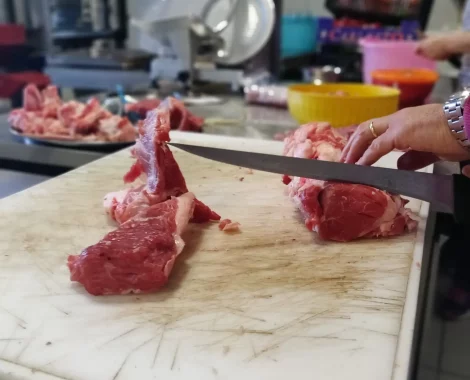 Persona taglia carne su un tagliere in cucina.