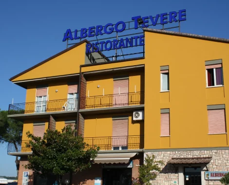 Edificio giallo con insegna "Albergo Tevere Ristorante".
